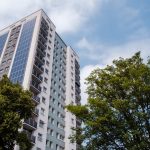 Tall block of flats, trees and blue sky